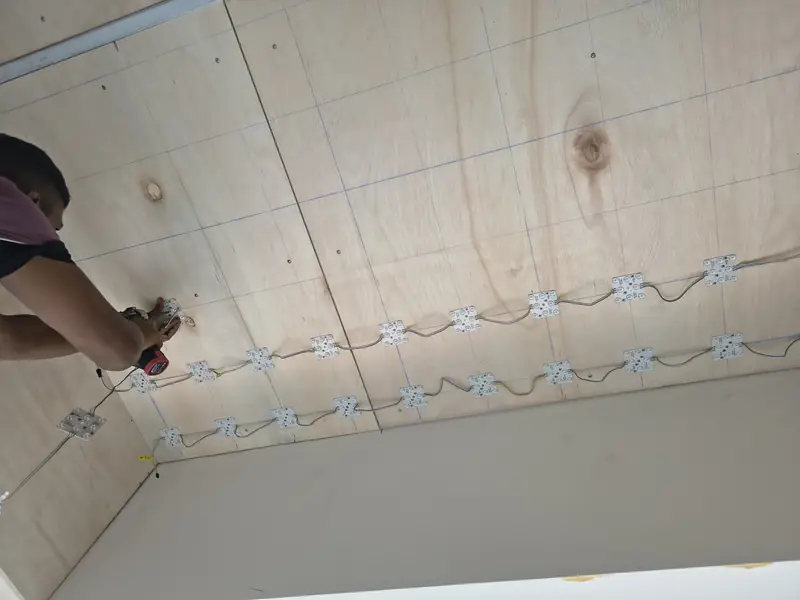 Electrician installing LED wiring on a ceiling before boarding for a ceiling partition Singapore job
